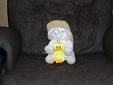A small white elephant with a straw cowboy hat holding a stuffed duckling