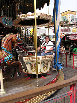 A child holding a stuffed lion while on a merry-go-round